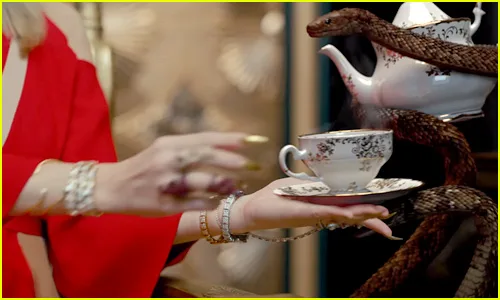 Η Taylor Swift κρατάει ένα φλιτζάνι τσάι ενώ ένα φίδι τυλίγεται γύρω από μια τσαγιέρα.