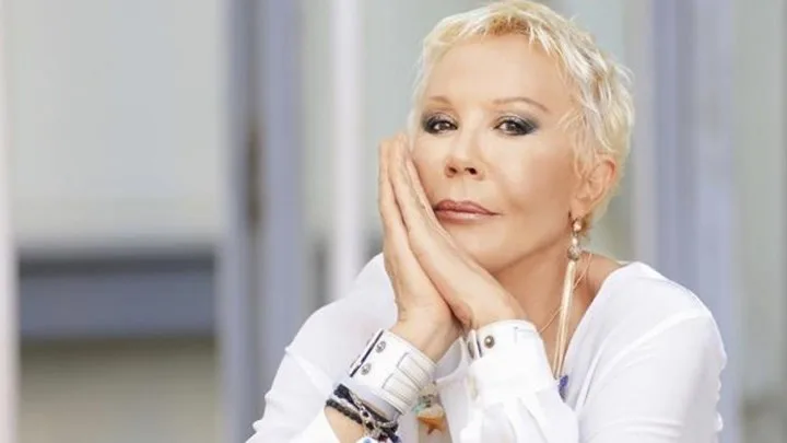 Πορτρέτο της Ζωής Λάσκαρη με ξανθά κοντά μαλλιά και λευκό πουκάμισο.