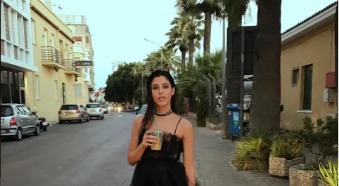 Η Demy περπατάει στο δρόμο κρατώντας καφέ