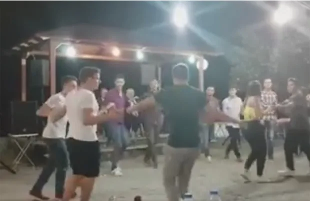 Άνθρωποι χορεύουν σε ελληνικό πανηγύρι τη νύχτα.