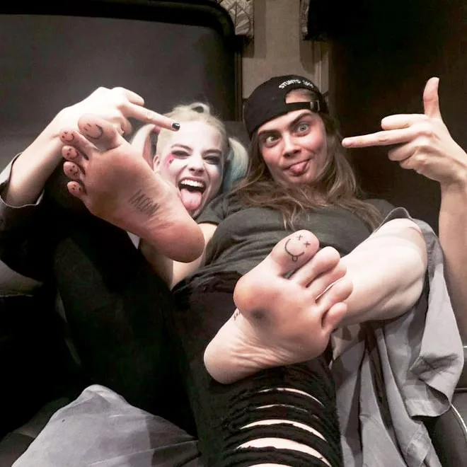 Η Cara Delevingne και η Margot Robbie δείχνουν τα τατουάζ στα δάχτυλα των ποδιών τους.