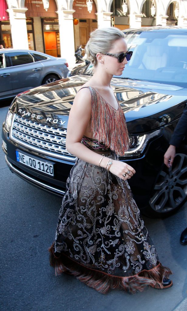 Η Jennifer Lawrence με boho φόρεμα και γυαλιά ηλίου μπροστά από ένα μαύρο Range Rover.