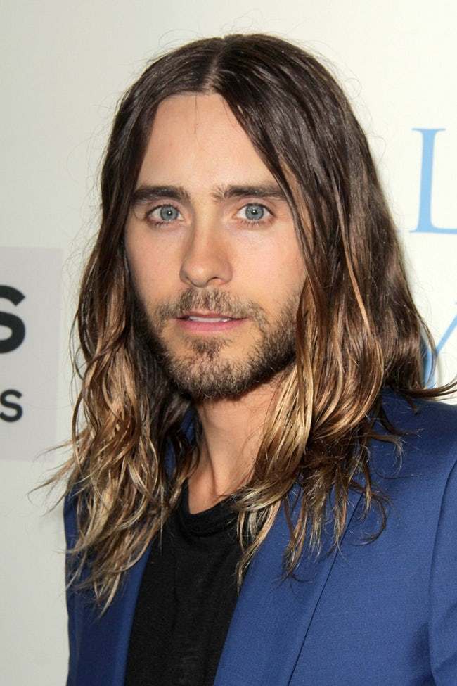 Πορτρέτο του Jared Leto με μακριά μαλλιά και μπλε σακάκι.