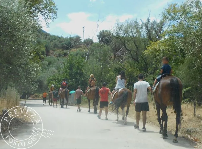 Ομάδα ανθρώπων κάνει ιππασία σε χωματόδρομο μέσα στη φύση.