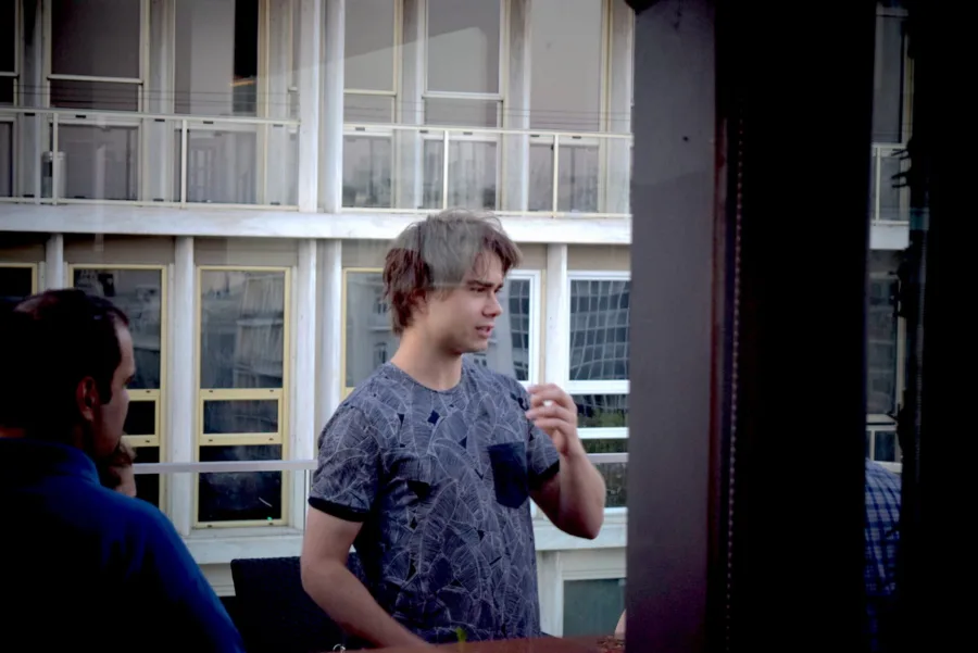Ο Alexander Rybak σε εξωτερικό χώρο με κτίριο στο φόντο.