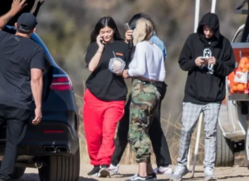 Η Kylie Jenner με κόκκινη φόρμα και μαύρο t-shirt μιλάει στο κινητό της σε εξωτερικό χώρο.