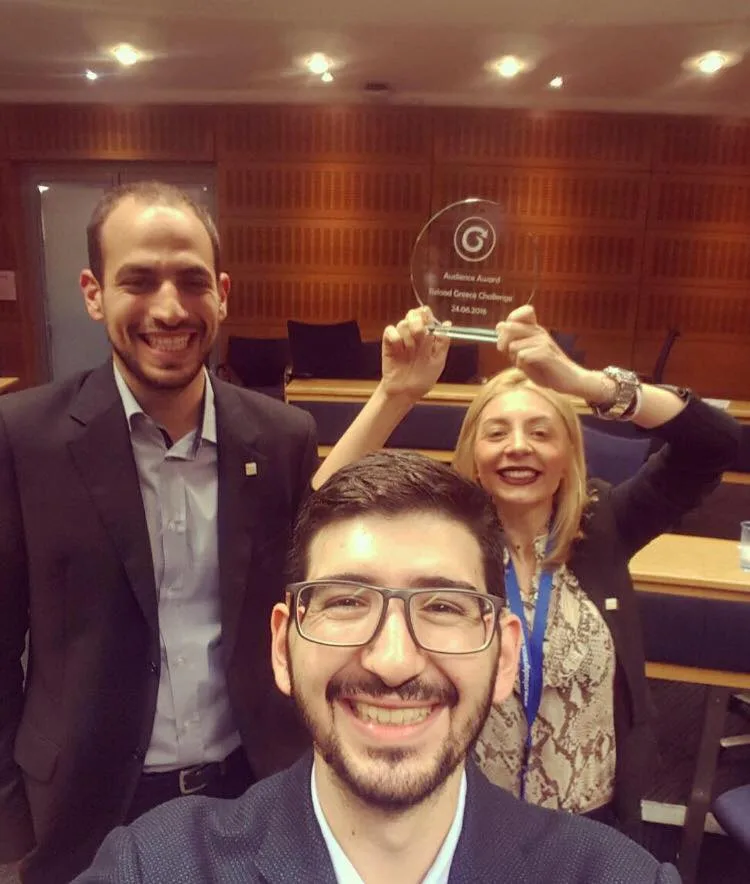 Τρία μέλη της ομάδας Owiwi χαμογελούν κρατώντας ένα βραβείο.