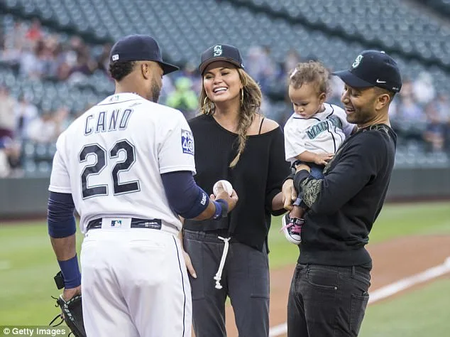 Ο John Legend και η Chrissy Teigen με το παιδί τους σε γήπεδο μπέιζμπολ.