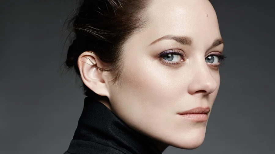 Κοντινό πορτρέτο της Marion Cotillard με πιασμένα μαλλιά και κομψό μακιγιάζ.