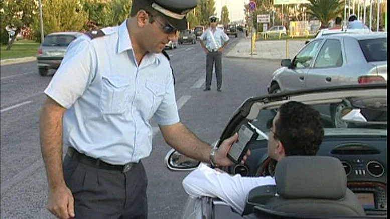 Αστυνομικός της τροχαίας πραγματοποιεί έλεγχο αλκοτέστ σε οδηγό αυτοκινήτου.