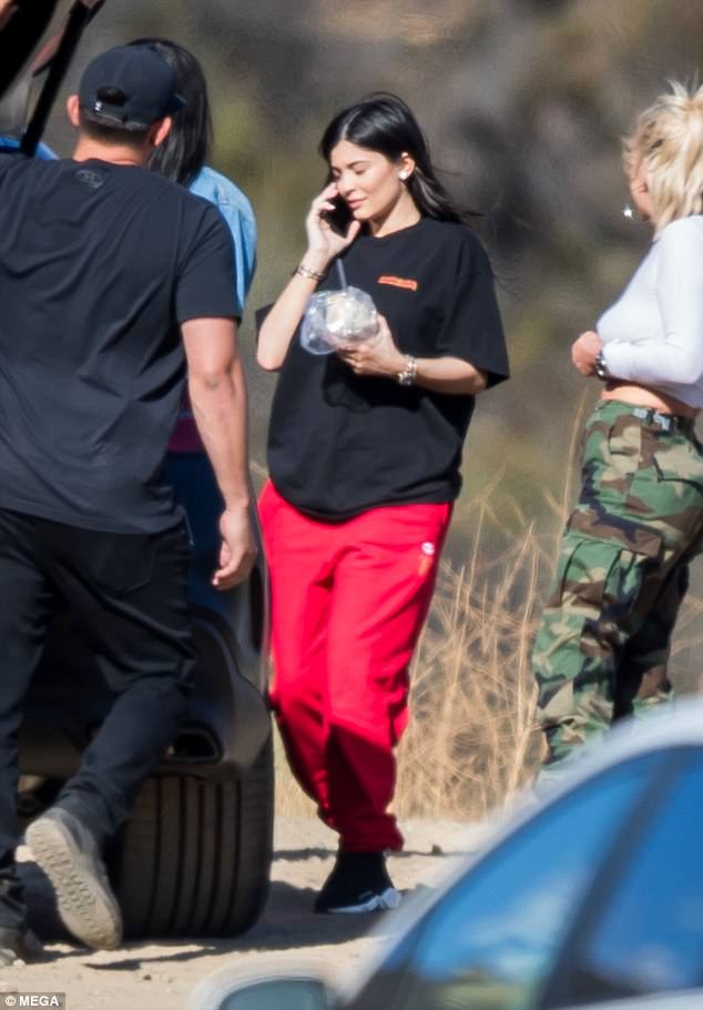 Η Kylie Jenner με μαύρο t-shirt και κόκκινη φόρμα μιλάει στο κινητό της.