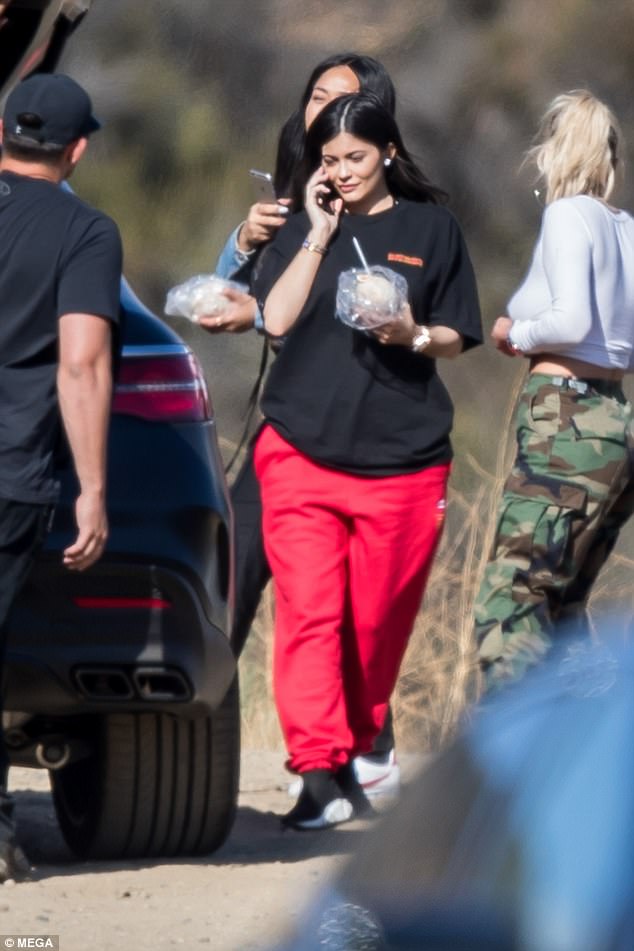 Η Kylie Jenner με μαύρο t-shirt και κόκκινη φόρμα σε εξωτερικό χώρο.