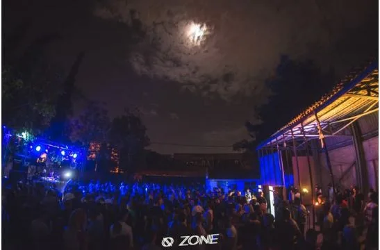 Πλήθος κόσμου σε υπαίθριο DJ set τη νύχτα υπό το φως του φεγγαριού.