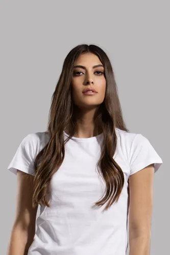 Γυναίκα με λευκό t-shirt και μακριά καστανά μαλλιά σε γκρι φόντο.