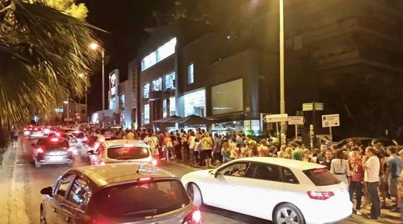 Πλήθος κόσμου και ουρές έξω από κτίριο γυμναστηρίου τη νύχτα.