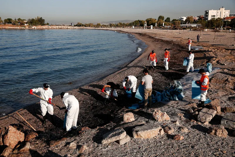 Συνεργεία καθαρίζουν παραλία στη Γλυφάδα από την πετρελαιοκηλίδα μετά τη βύθιση δεξαμενόπλοιου στον Σαρωνικό.