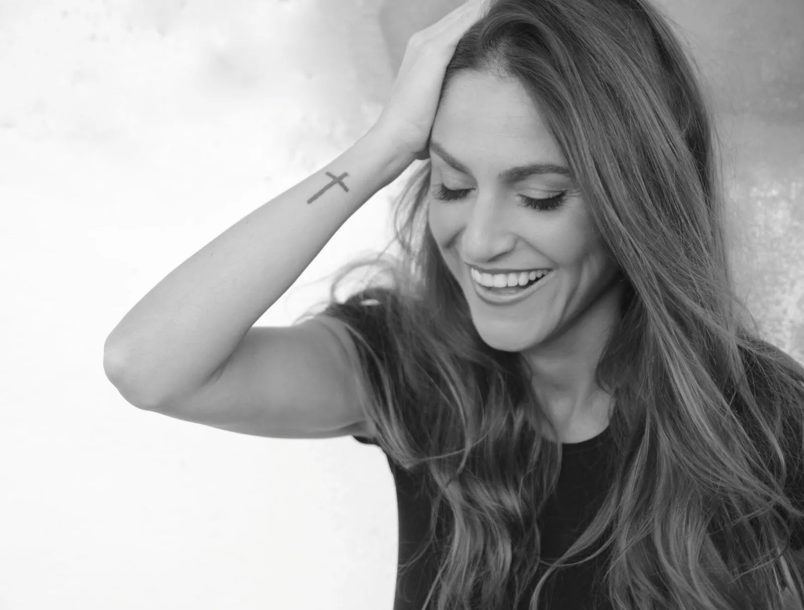 Η Isabela Clerc χαμογελάει με το χέρι στο κεφάλι σε ασπρόμαυρη φωτογραφία.