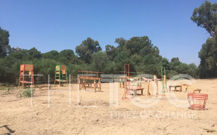 Στίβος μάχης του Survival σε αμμώδη περιοχή με ξύλινες κατασκευές.