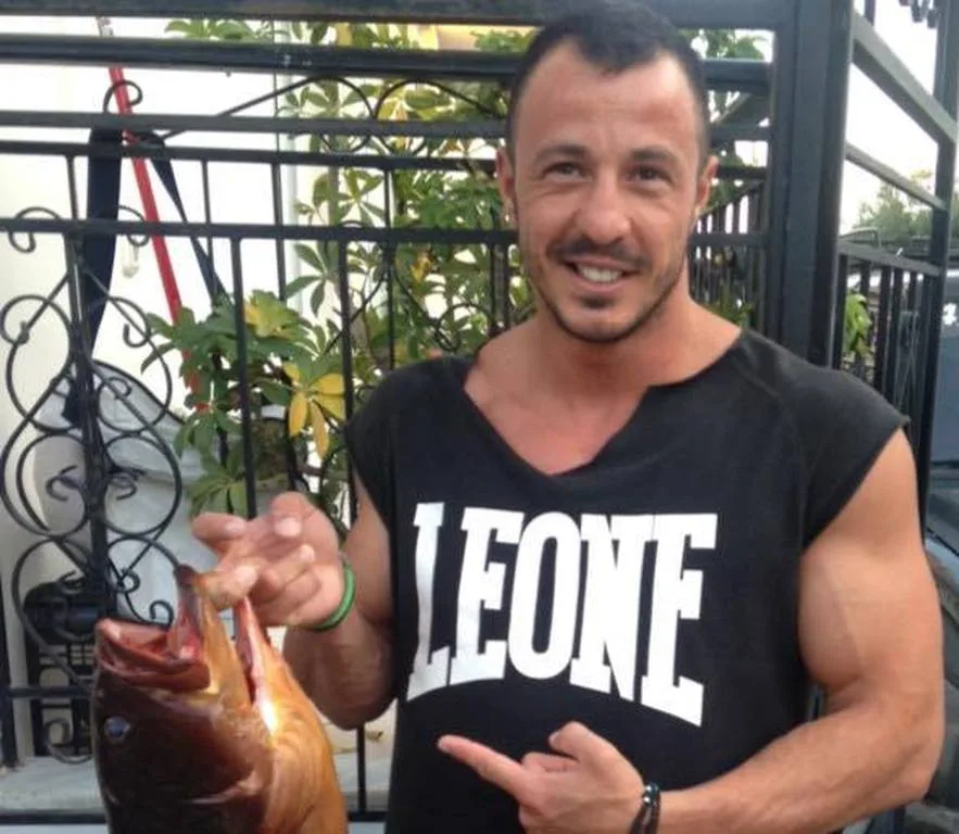Άνδρας με αθλητική μπλούζα κρατάει ένα μεγάλο ψάρι.