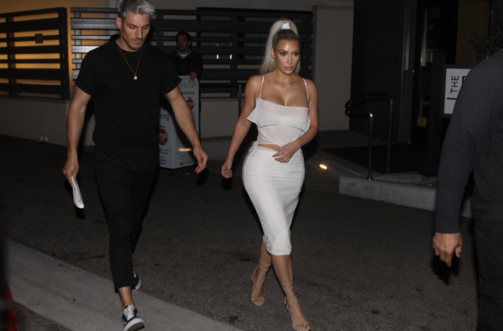 Η Kim Kardashian με λευκό φόρεμα περπατάει έξω το βράδυ.