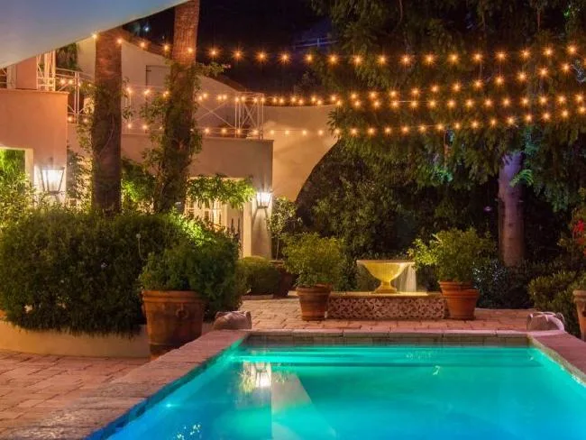Πισίνα και κήπος πολυτελούς έπαυλης στο Beverly Hills τη νύχτα.