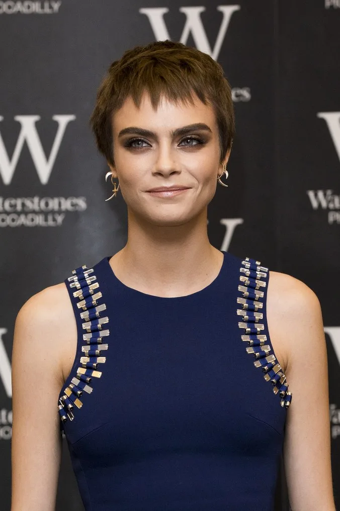 Η Cara Delevingne με κοντό καστανό μαλλί και μπλε φόρεμα.