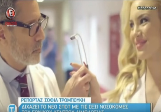 Στιγμιότυπο από τηλεοπτικό ρεπορτάζ με έναν άνδρα και μια ξανθιά γυναίκα.