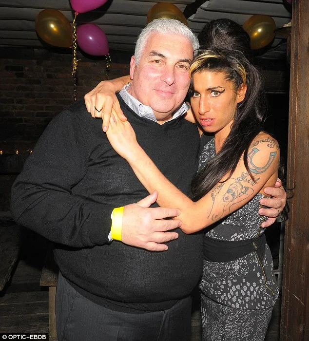 Η Amy Winehouse αγκαλιά με έναν άνδρα σε εσωτερικό χώρο με μπαλόνια.