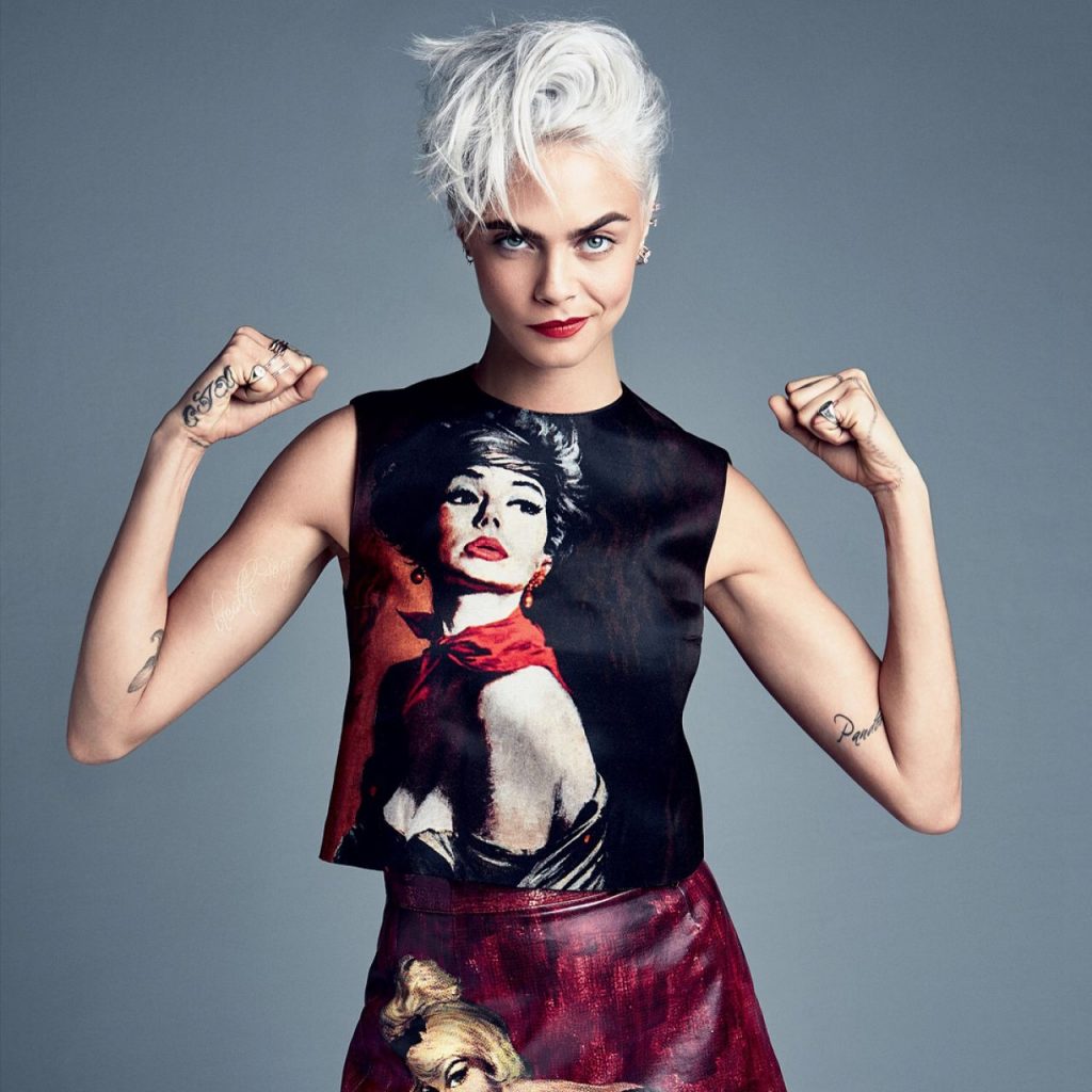 Η Cara Delevingne με κοντά πλατινέ μαλλιά και μπλούζα με τύπωμα γυναίκας.
