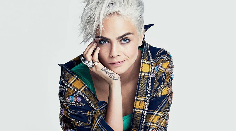 Η Cara Delevingne με κοντά πλατινέ μαλλιά και καρό σακάκι.