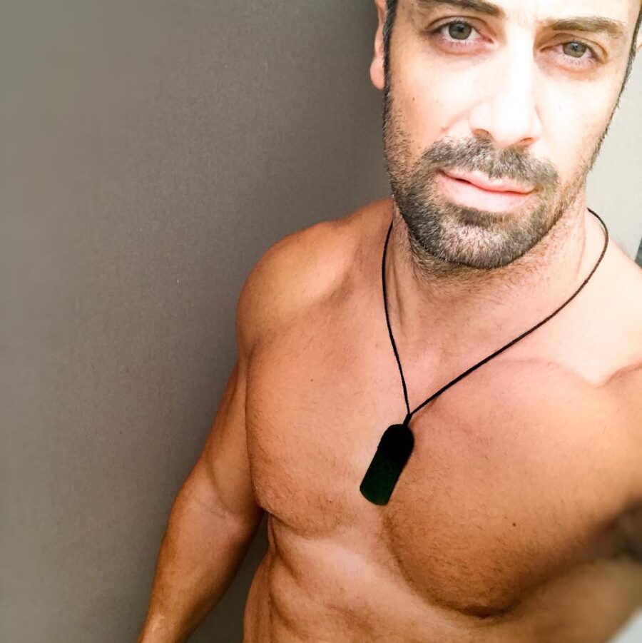 Ένας άνδρας personal trainer με αθλητικό σώμα και μενταγιόν.