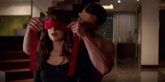 Σκηνή από την ταινία Fifty Shades Freed με έναν άνδρα να δένει τα μάτια μιας γυναίκας με κόκκινη κορδέλα.