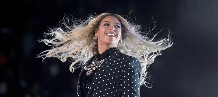 Η Beyonce στη σκηνή με μαύρο πουά σακάκι και τα μαλλιά της να ανεμίζουν.