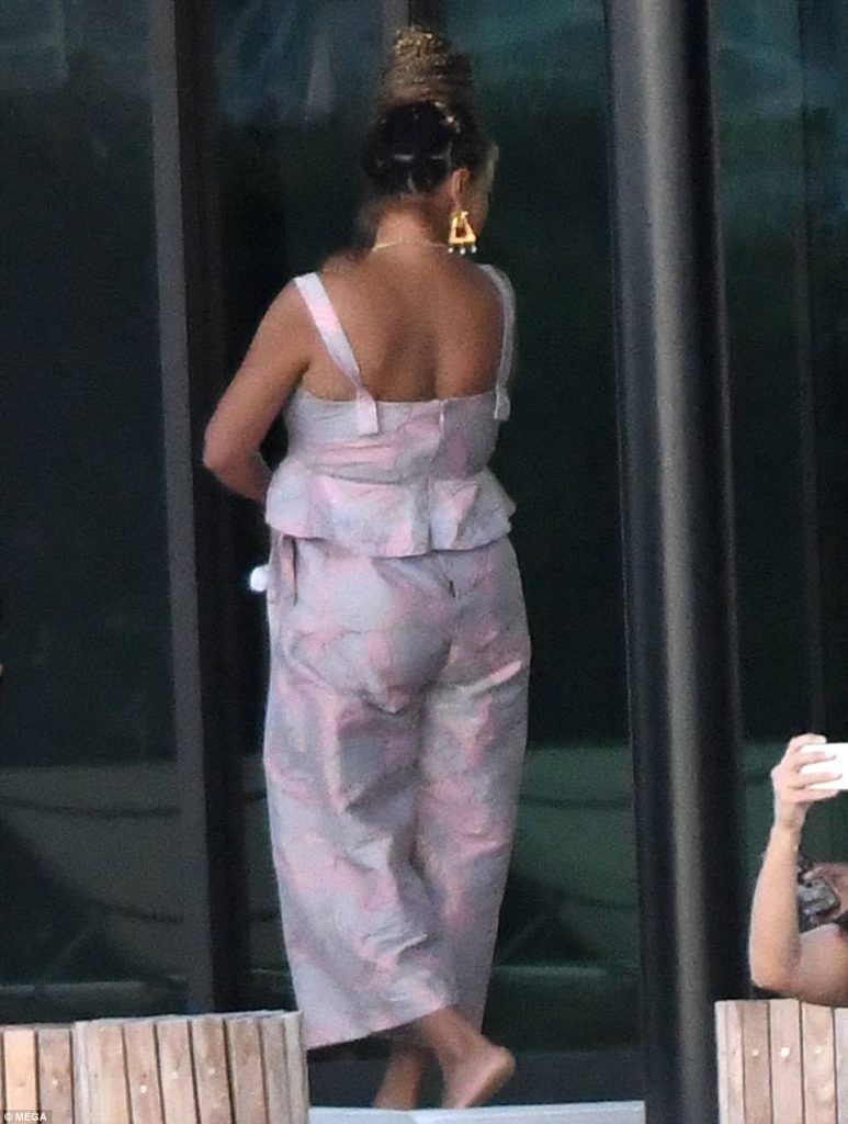 Η Beyoncé με πλάτη, φορώντας εμπριμέ σύνολο και χρυσά σκουλαρίκια, κρατώντας ένα από τα δίδυμα μωρά της.
