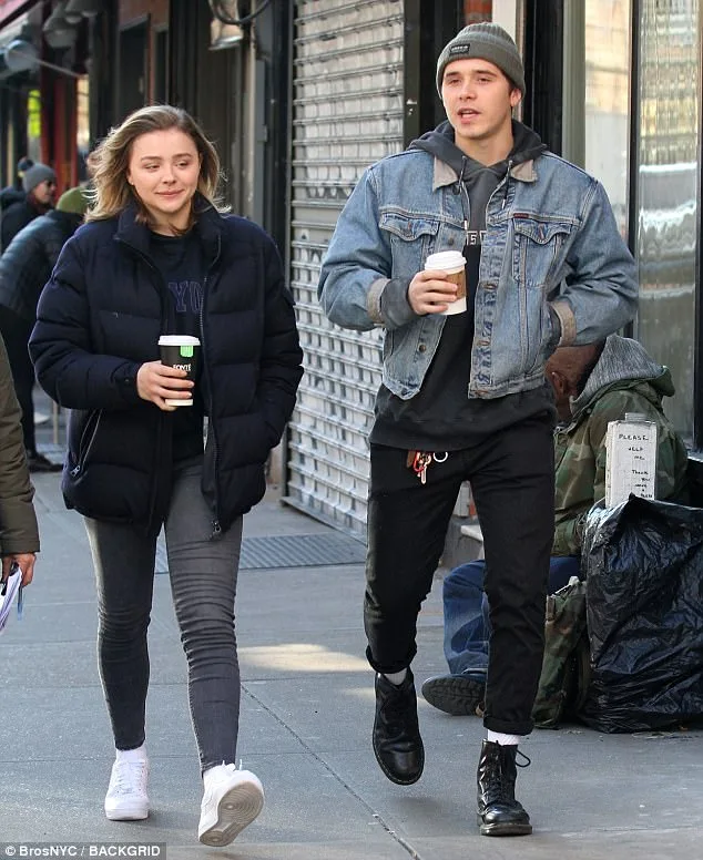 Ο Brooklyn Beckham και η Chloë Grace Moretz περπατούν στο δρόμο κρατώντας καφέ.