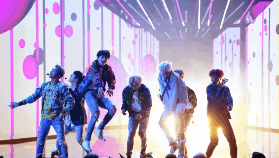 K-pop συγκρότημα σε δυναμική χορογραφία στη σκηνή των American Music Awards.
