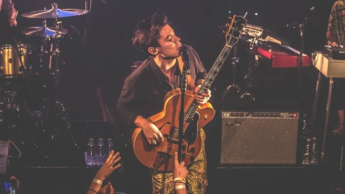 Ο Harry Styles παίζει κιθάρα και τραγουδάει σε συναυλία.