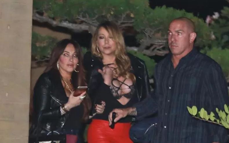 Η Mariah Carey με μαύρο δερμάτινο τζάκετ και κόκκινο παντελόνι σε βραδινή έξοδο.