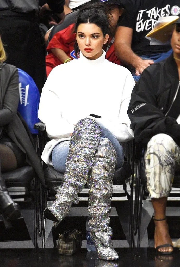 Η Kendall Jenner με λευκό ζιβάγκο και ασημί μπότες με κρύσταλλα σε αγώνα μπάσκετ.