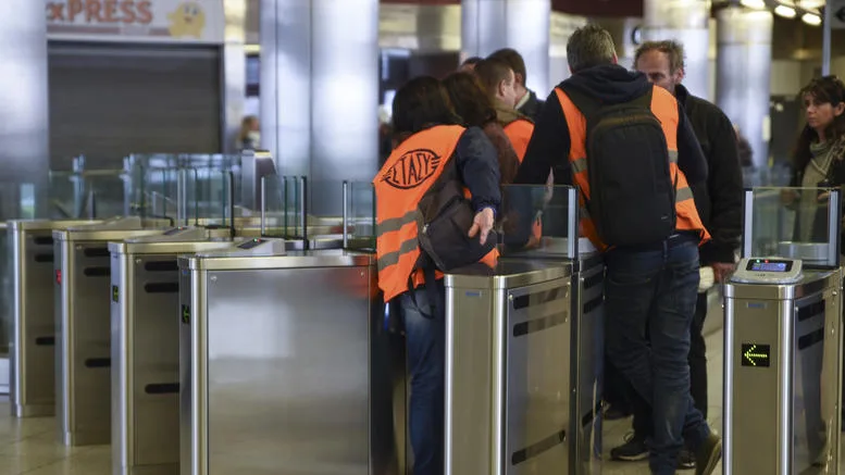 Άνθρωποι σε σταθμό του μετρό μπροστά από πύλες ελέγχου ηλεκτρονικού εισιτηρίου.