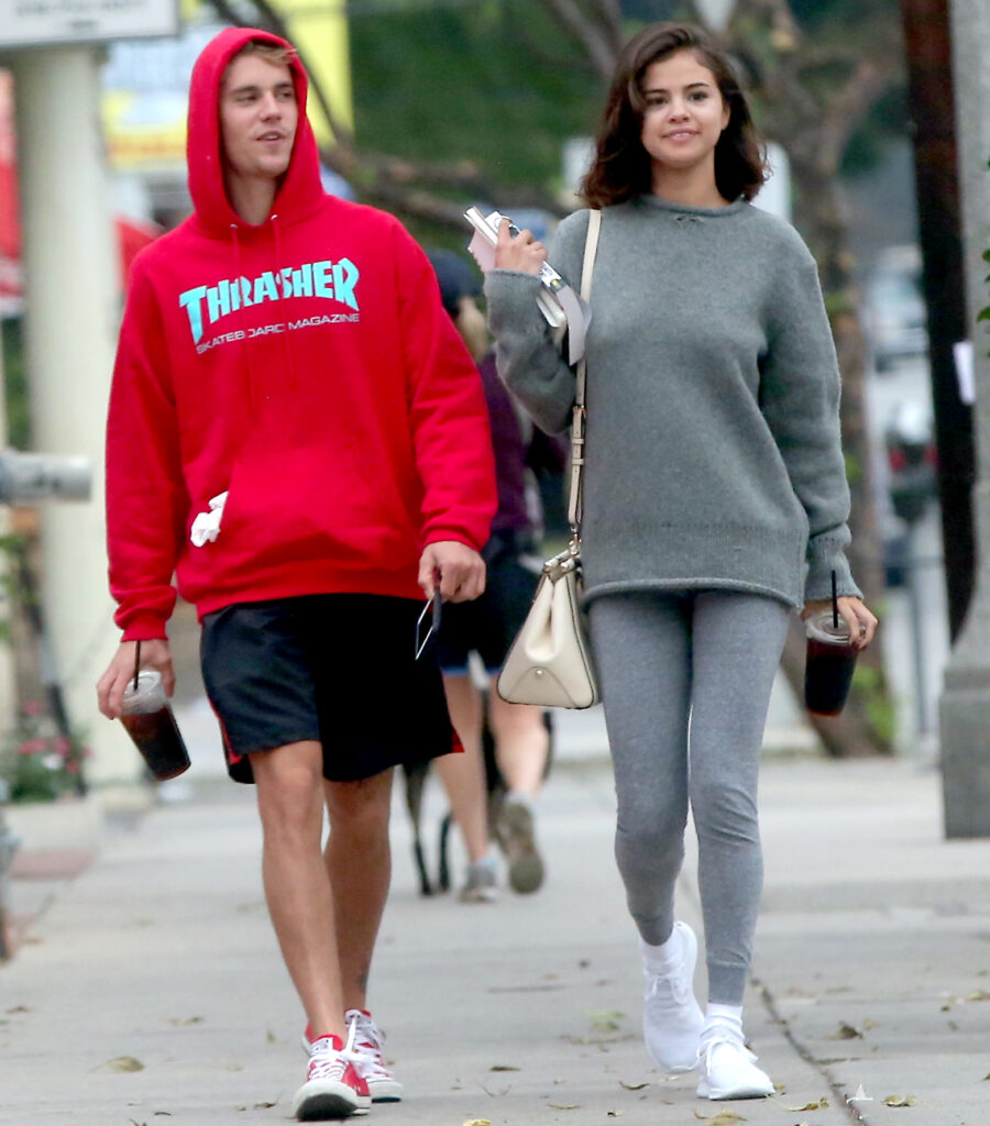 Ο Justin Bieber και η Selena Gomez περπατούν στο δρόμο κρατώντας καφέ.