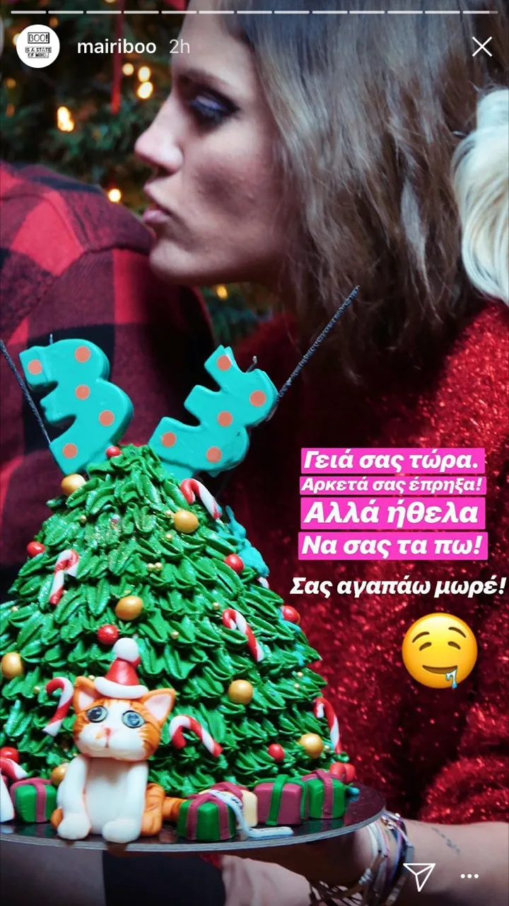 Η Μαίρη Συνατσάκη μπροστά από μια τούρτα σε σχήμα χριστουγεννιάτικου δέντρου.