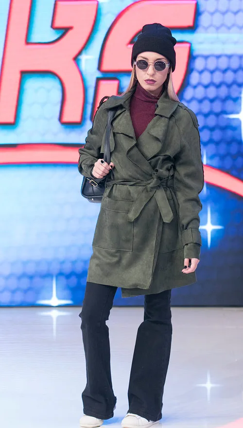 Παίκτρια του My Style Rocks με λαδί παλτό, μαύρο σκούφο και γυαλιά ηλίου.