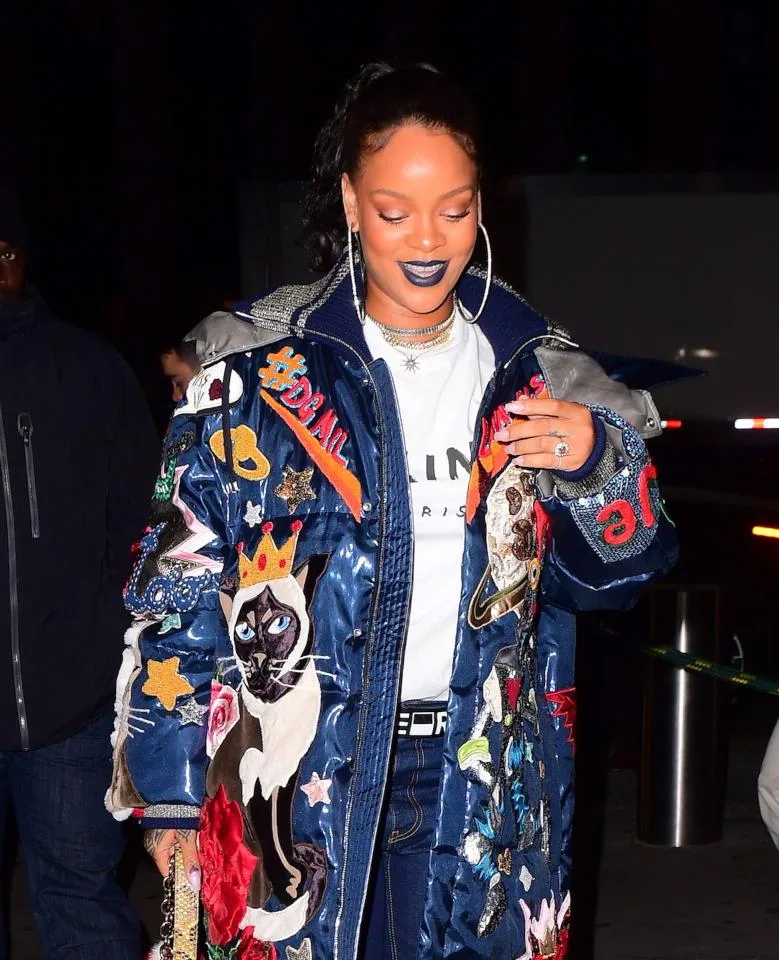 Η Rihanna με εντυπωσιακό μπλε μπουφάν με κεντήματα και μεγάλο μονόπετρο στο χέρι.