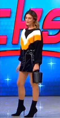 Παίκτρια του My Style Rocks με μαύρη φούστα και πουλόβερ.