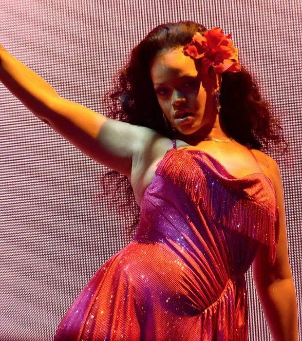 Η Rihanna στη σκηνή των Grammys με κόκκινο φόρεμα και λουλούδι στα μαλλιά.