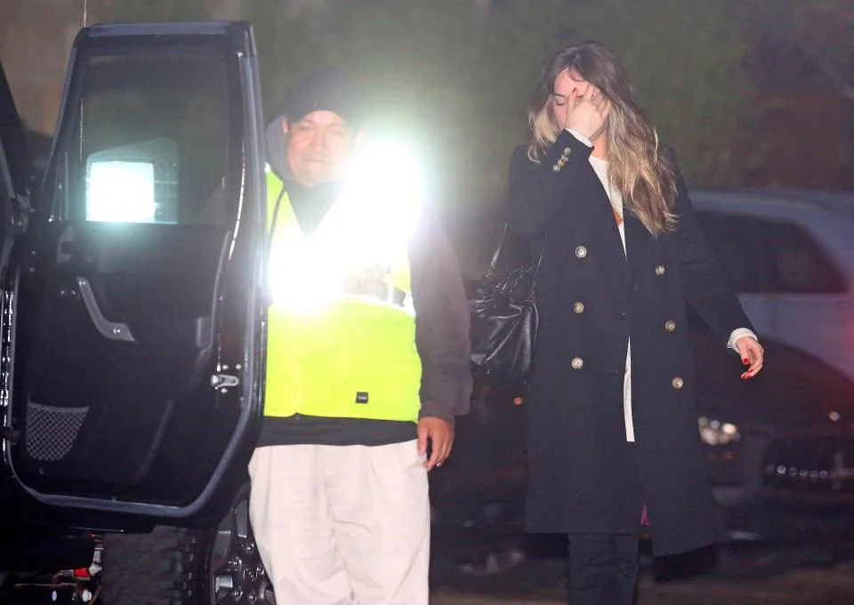 Η Dakota Johnson περπατά δίπλα σε ένα αυτοκίνητο τη νύχτα.