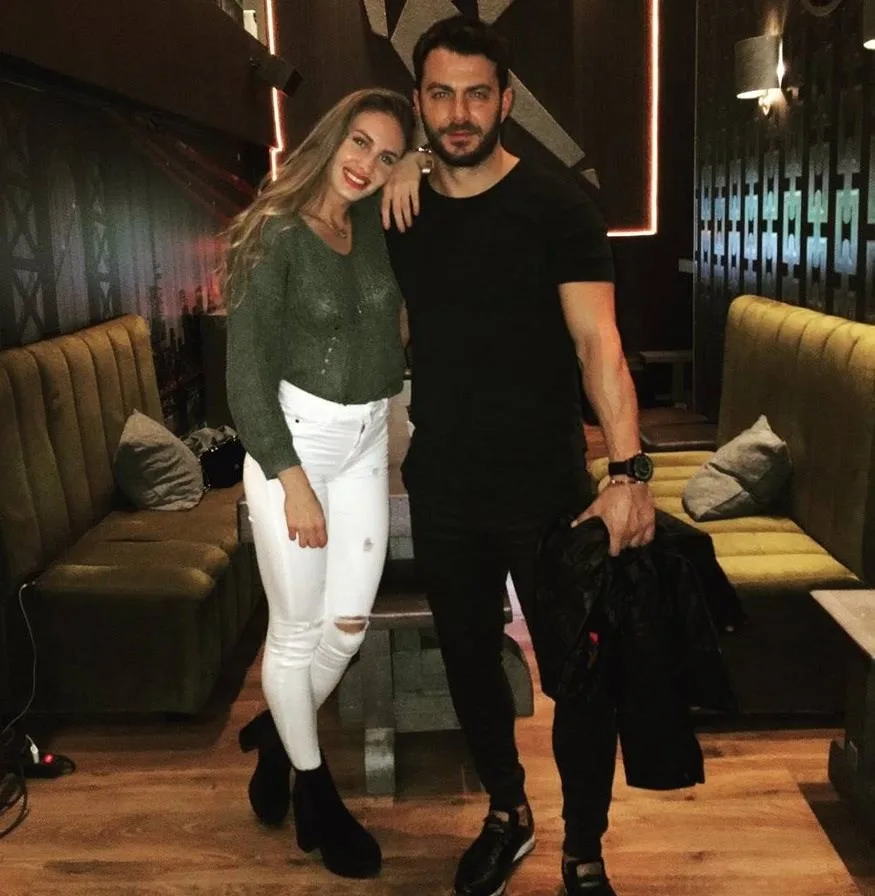Ο Γιώργος Αγγελόπουλος ποζάρει με μια γυναίκα σε εσωτερικό χώρο.
