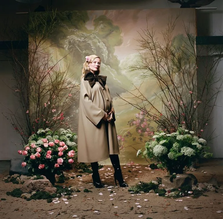 Η Kirsten Dunst ποζάρει έγκυος σε ένα καλλιτεχνικό σκηνικό με λουλούδια.