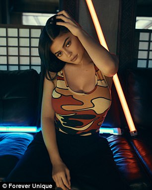 Η Kylie Jenner ποζάρει σε καναπέ με φόντο φωτεινούς σωλήνες νέον.